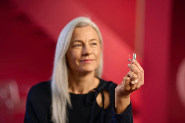 Ein Frau hält ein ReSound Savi Hinter-dem-Ohr-Hörgerät in der Hand
