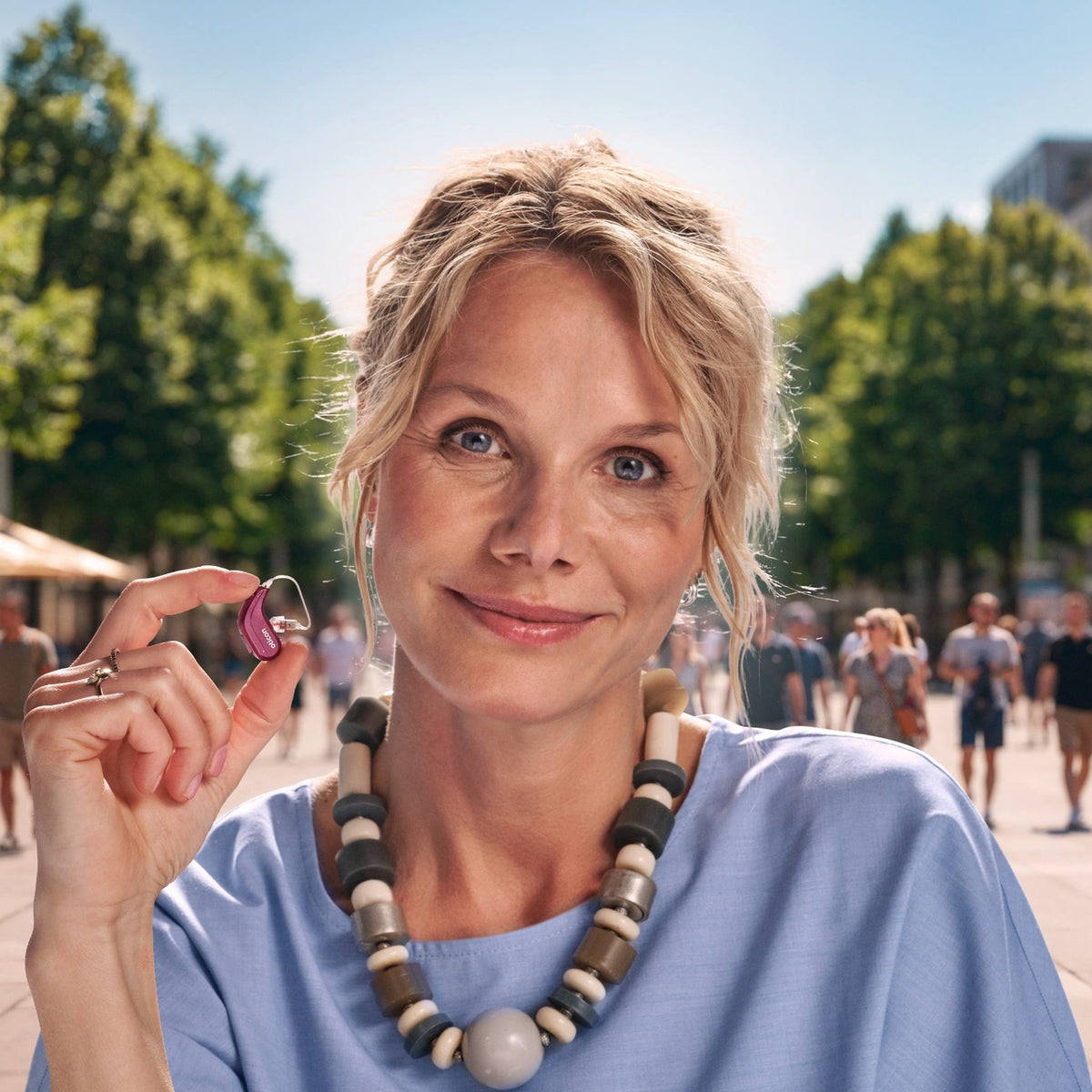 Frau hält Oticon Reveal Hinter-dem-Ohr-Hörgerät in der Hand