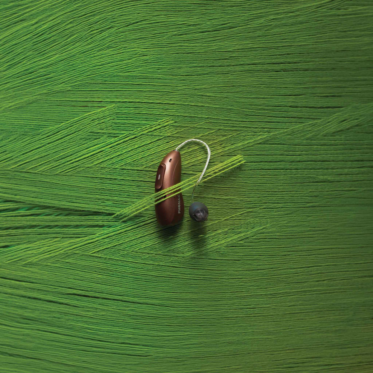 Phonak Audeo Infinio Ultra Hinter-dem-Ohr-Hörgerät vor einer grünen Stoffwand