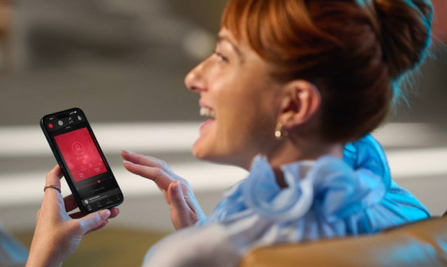 Eine Frau nutzt ReSound Vivia Hinter-dem-Ohr-Hörgeräte mit ihrem iPhone